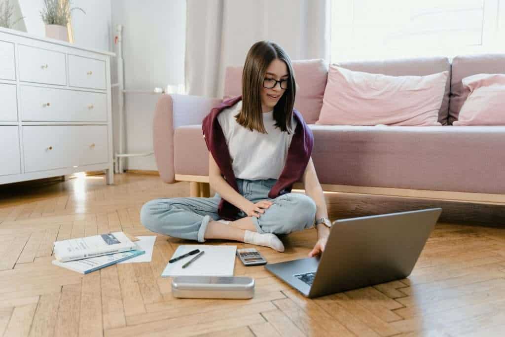 Teenager studying on her laptop, supported by quality care and regular Regulation 44 inspections.